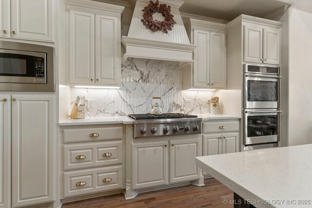 9475 E 107th Pl S, Bixby, OK 74133 - kitchen featuring premium range hood, stainless steel appliances, tasteful backsplash, and wood finished floors