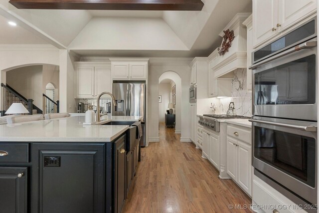 9475 E 107th Pl S, Bixby, OK 74133 - kitchen with arched walkways, appliances with stainless steel finishes, white cabinetry, light countertops, and decorative backsplash