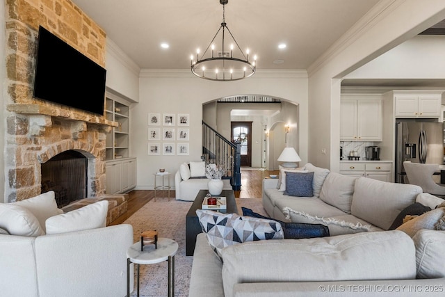 9475 E 107th Pl S, Bixby, OK 74133 - living area featuring arched walkways, a chandelier, wood finished floors, a fireplace, and stairway