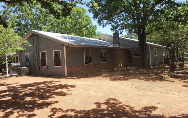 5328 Monroe Rd, Kingston, OK 73439 - view of front of home featuring brick siding, a chimney, central air condition unit, metal roof, and fence