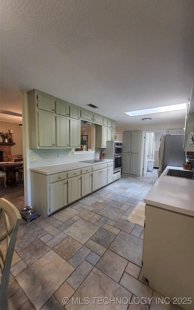 5328 Monroe Rd, Kingston, OK 73439 - kitchen featuring light countertops, stone tile floors, stainless steel appliances, and green cabinets