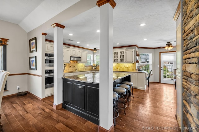 kitchen featuring ceiling fan, under cabinet range hood, decorative columns, crown molding, and recessed lighting