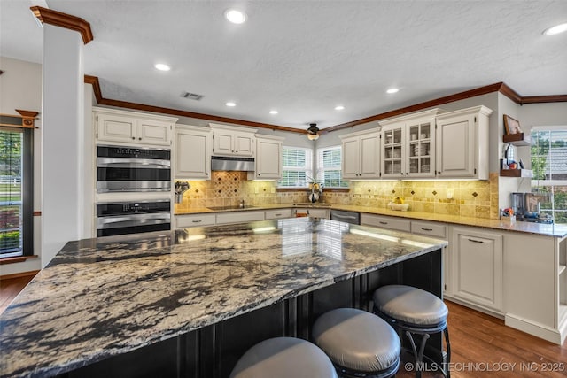 kitchen featuring appliances with stainless steel finishes, dark wood-style flooring, plenty of natural light, recessed lighting, and crown molding