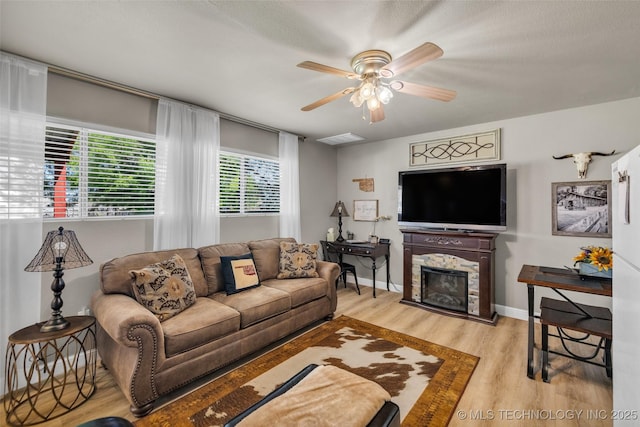living room featuring wood finished floors, a ceiling fan, and a fireplace