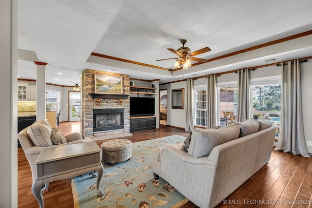 living area featuring a ceiling fan, ornamental molding, a tray ceiling, wood finished floors, and a textured ceiling