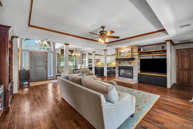 living room with a raised ceiling, a chandelier, ceiling fan, crown molding, and dark wood-type flooring