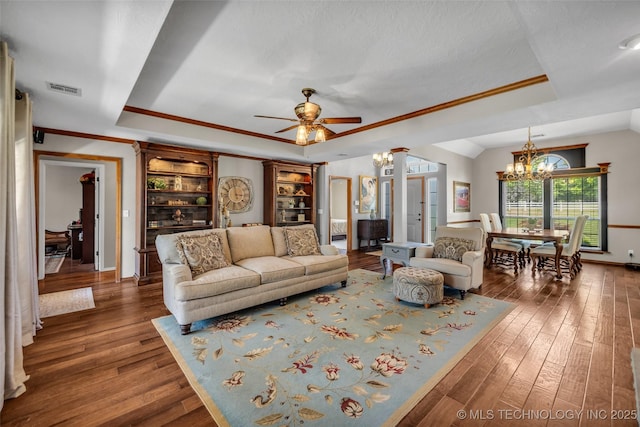 living area featuring a raised ceiling, a chandelier, crown molding, hardwood / wood-style flooring, and a ceiling fan