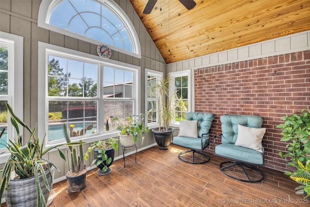 sunroom / solarium with plenty of natural light, wooden ceiling, wood finished floors, a ceiling fan, and high vaulted ceiling
