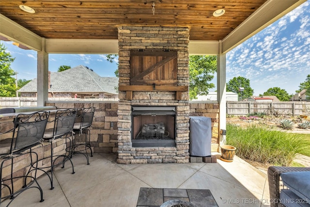 view of patio featuring an outdoor stone fireplace and fence