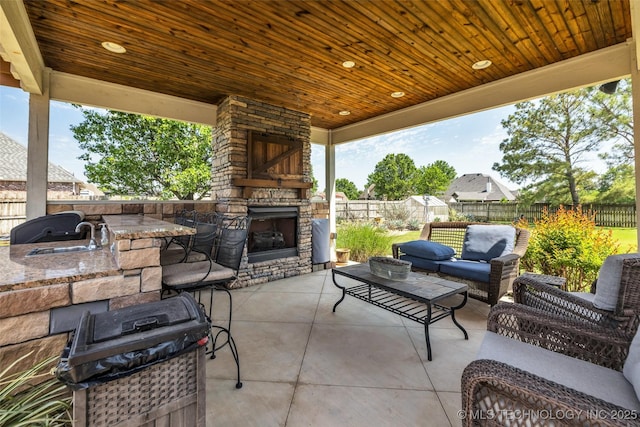 view of patio / terrace with area for grilling, a fenced backyard, an outdoor living space with a fireplace, and a sink