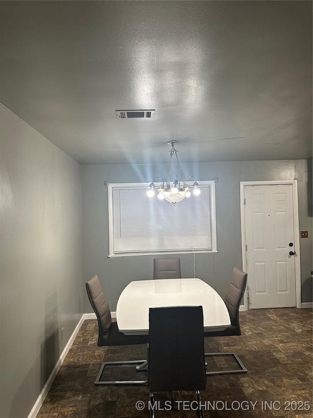dining space with a chandelier, baseboards, and stone finish flooring