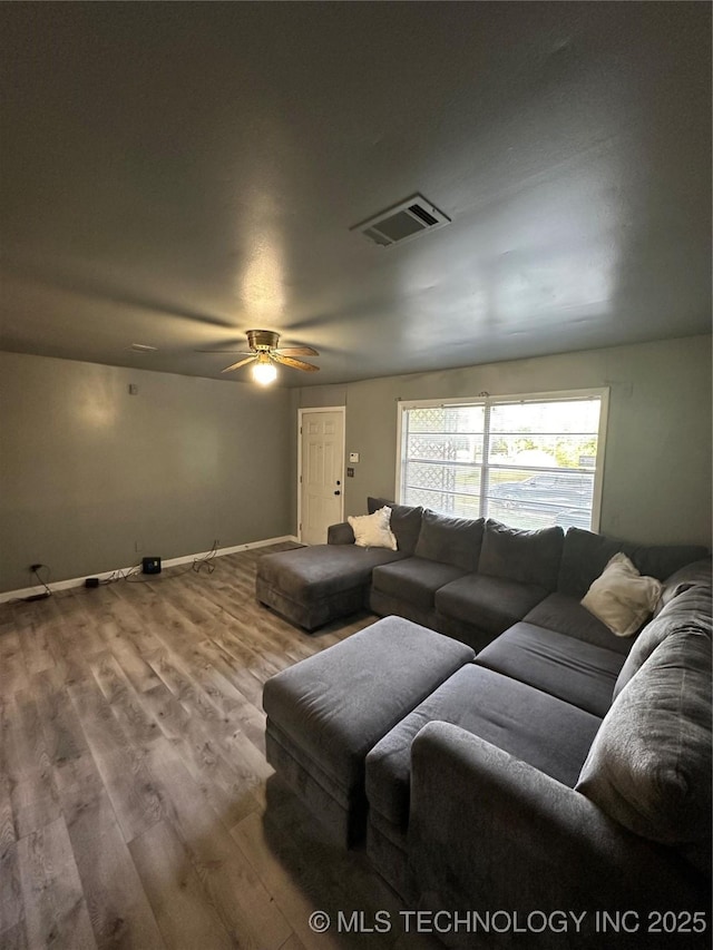 living room featuring ceiling fan, wood finished floors, and baseboards