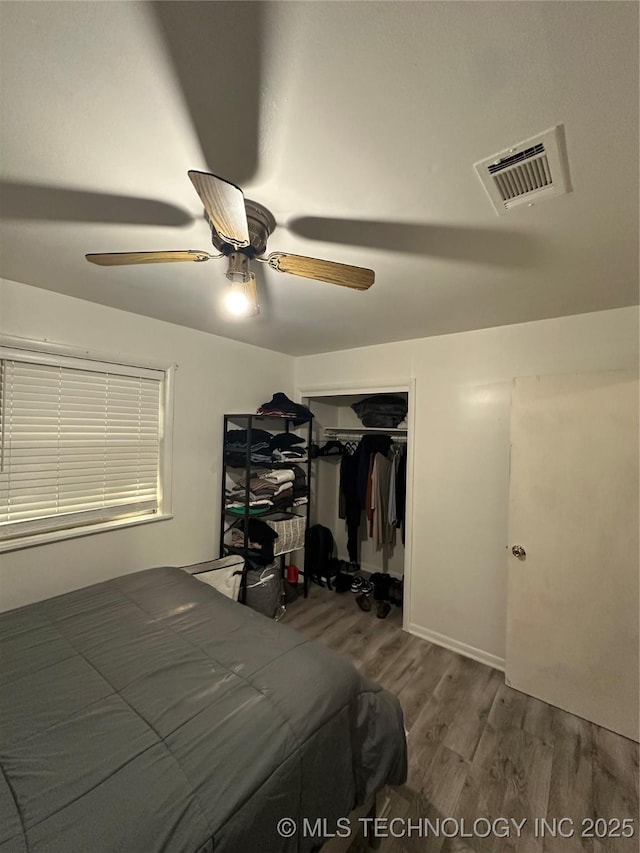 bedroom featuring wood finished floors, ceiling fan, and a closet