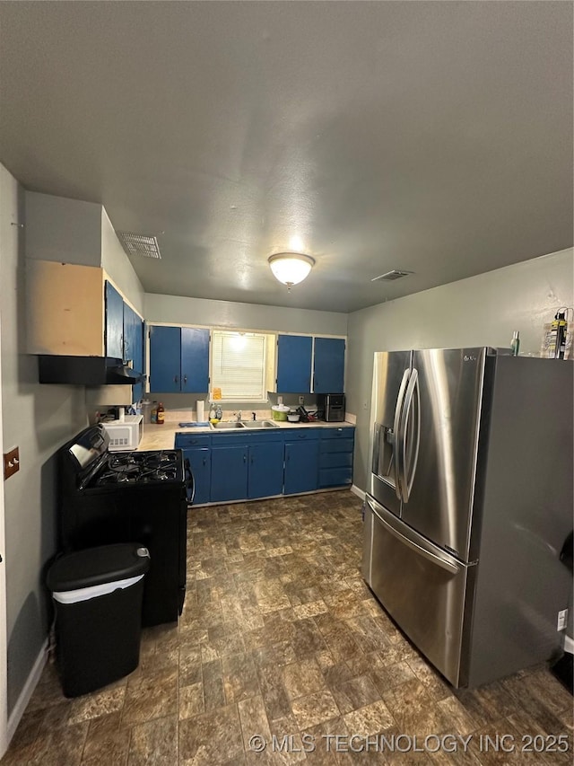 kitchen featuring blue cabinets, stainless steel refrigerator with ice dispenser, black gas stove, light countertops, and under cabinet range hood