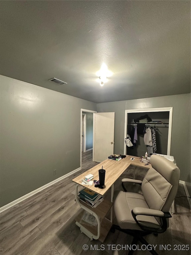 office with wood finished floors, baseboards, and a textured ceiling