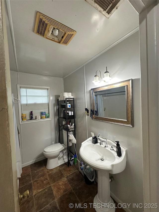 half bath featuring toilet, stone finish flooring, and a sink
