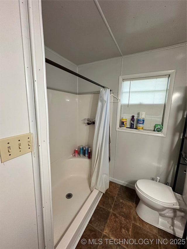 bathroom featuring curtained shower, stone tile floors, and toilet