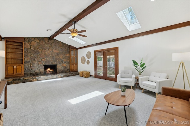 living room featuring a skylight, ceiling fan, a fireplace, and carpet floors