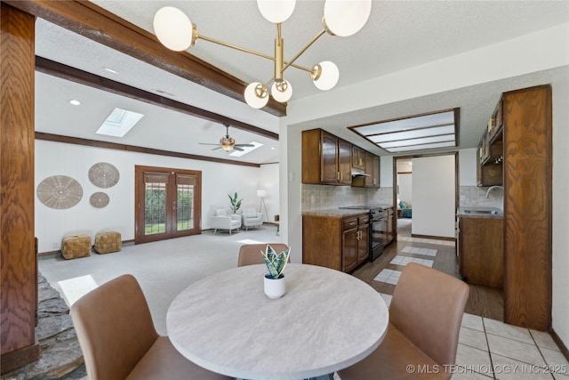 dining area with a chandelier, beamed ceiling, a skylight, a ceiling fan, and a textured ceiling