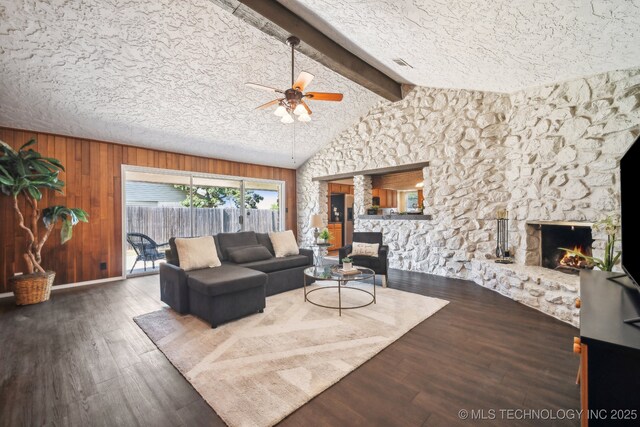 6505 E 47th St, Tulsa, OK 74145 - living room with a stone fireplace, a ceiling fan, wood finished floors, and wooden walls