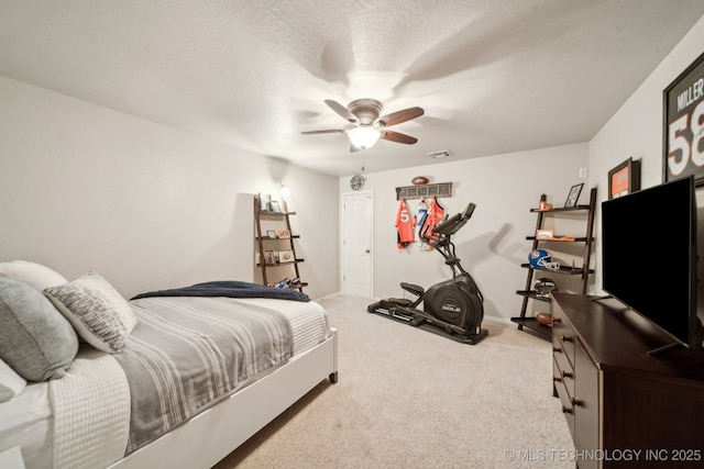 carpeted bedroom with ceiling fan and a textured ceiling