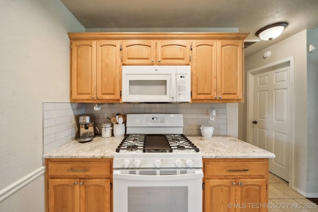 kitchen with white appliances, decorative backsplash, light tile patterned flooring, and light stone countertops