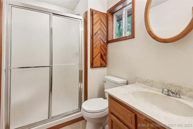 bathroom featuring a stall shower, toilet, vanity, and a textured ceiling