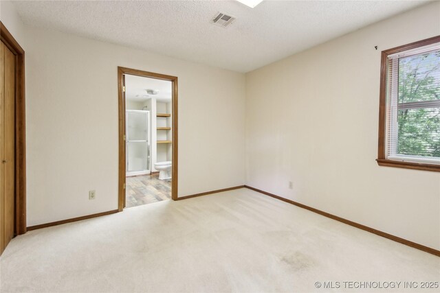 unfurnished room featuring light colored carpet, baseboards, and a textured ceiling