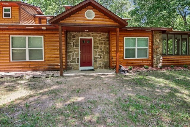view of front of property featuring stone siding and faux log siding