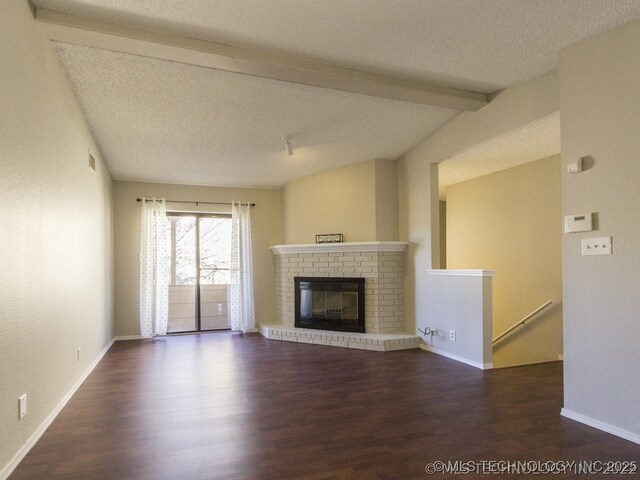 9023 S Delaware Ave Unit 605, Tulsa, OK 74137 - unfurnished living room featuring wood finished floors, beamed ceiling, a fireplace, and a textured ceiling