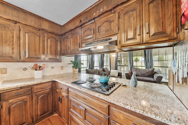 9599 E 155th Ave N, Owasso, OK 74055 - kitchen with electric stovetop, under cabinet range hood, light stone counters, tasteful backsplash, and a textured ceiling