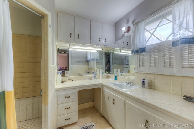 5102 S Columbia Ave, Tulsa, OK 74105 - bathroom with a tile shower, tile patterned floors, vanity, and decorative backsplash