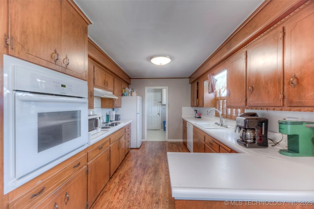 5102 S Columbia Ave, Tulsa, OK 74105 - kitchen with white appliances, a sink, under cabinet range hood, light countertops, and light wood-style floors