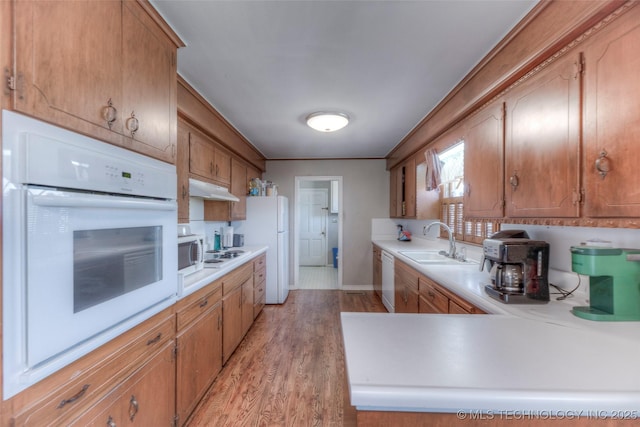 5102 S Columbia Ave, Tulsa, OK 74105 - kitchen featuring white appliances, under cabinet range hood, light countertops, light wood finished floors, and brown cabinets