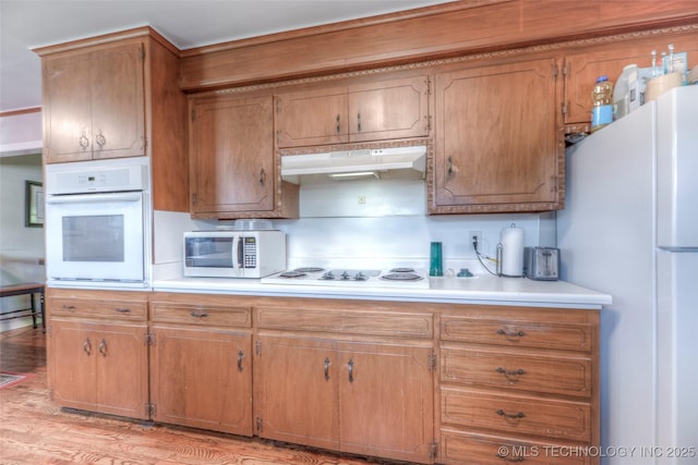 5102 S Columbia Ave, Tulsa, OK 74105 - kitchen featuring white appliances, under cabinet range hood, light countertops, light wood-style flooring, and brown cabinets