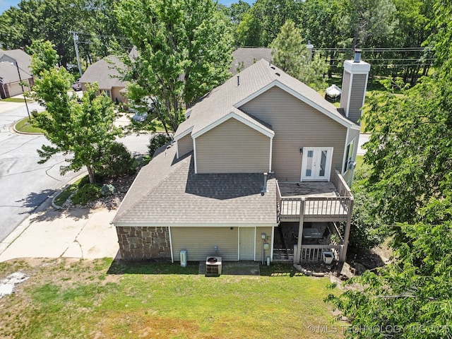rear view of house featuring french doors, a wooden deck, a yard, a chimney, and roof with shingles