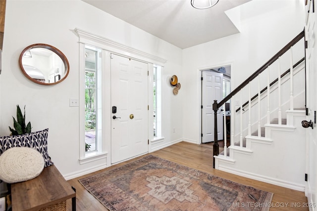 foyer featuring wood finished floors, baseboards, and stairs