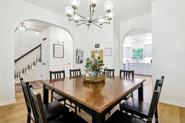 21304 S 4200th Rd, Claremore, OK 74019 - dining space with arched walkways, light wood-style flooring, a chandelier, and stairway