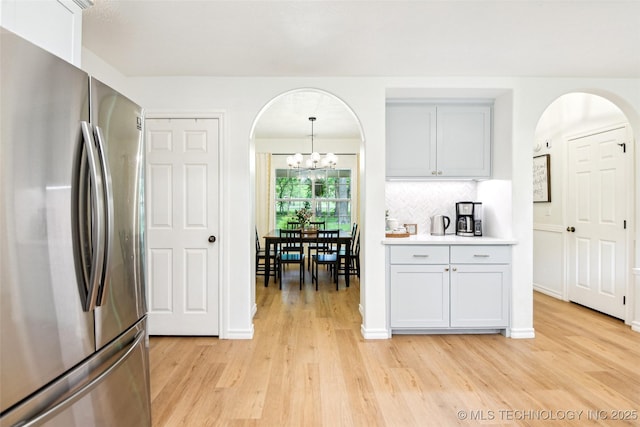 21304 S 4200th Rd, Claremore, OK 74019 - kitchen featuring freestanding refrigerator, arched walkways, light wood-style flooring, and a chandelier