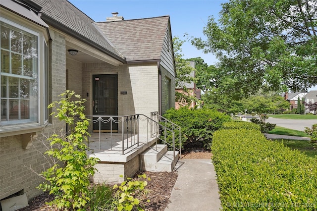 1208 E 29th St, Tulsa, OK 74114 - property entrance featuring brick siding, roof with shingles, and a chimney