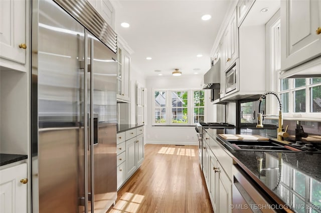 1208 E 29th St, Tulsa, OK 74114 - kitchen featuring built in appliances, a sink, baseboards, light wood finished floors, and white cabinets