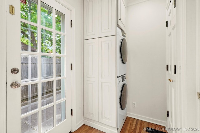 1208 E 29th St, Tulsa, OK 74114 - laundry area featuring stacked washer and clothes dryer, cabinet space, light wood-type flooring, and baseboards
