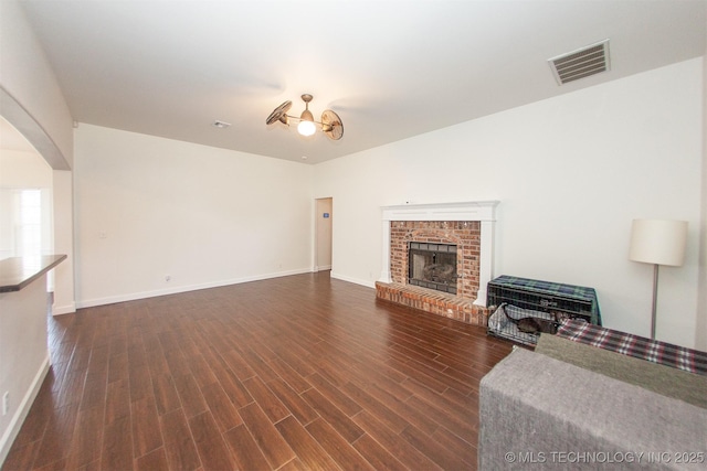 unfurnished living room featuring arched walkways, dark wood-type flooring, baseboards, and a fireplace
