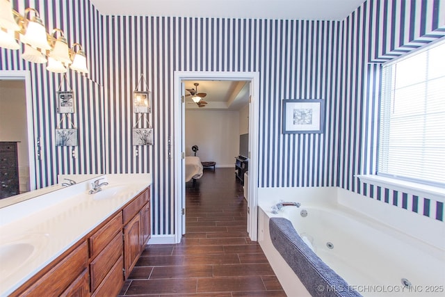 bathroom featuring wallpapered walls, baseboards, wood finished floors, a jetted tub, and double vanity