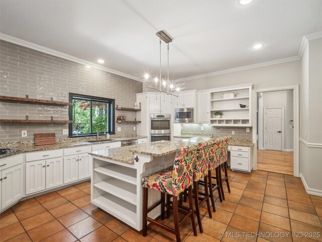 506 E 120th Pl S, Jenks, OK 74037 - kitchen with open shelves, stainless steel appliances, crown molding, tasteful backsplash, and a center island