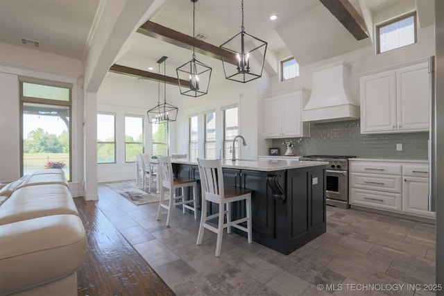 16958 E 45th St, Tulsa, OK 74134 - kitchen with high end stainless steel range, premium range hood, a chandelier, a center island with sink, and white cabinets
