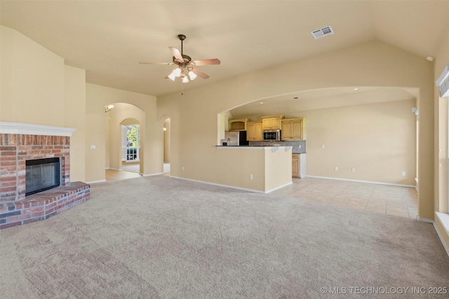 2000 W Vail St, Broken Arrow, OK 74012 - unfurnished living room with arched walkways, ceiling fan, light carpet, a brick fireplace, and light tile patterned floors