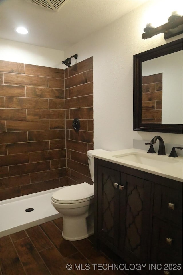 1185 E Pine St, Westville, OK 74965 - full bath featuring vanity, tiled shower, toilet, wood finish floors, and recessed lighting