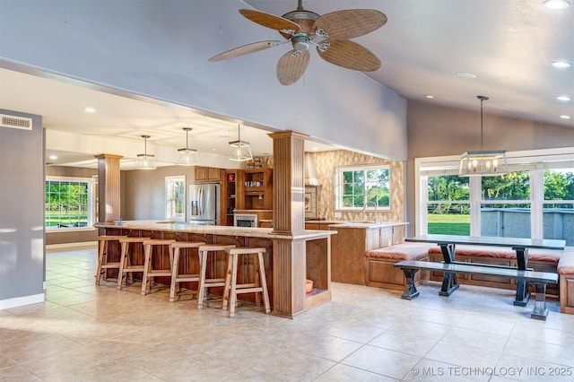 5378 W 450th Rd, Pryor, OK 74361 - kitchen featuring stainless steel refrigerator with ice dispenser, brown cabinetry, lofted ceiling, a center island, and recessed lighting