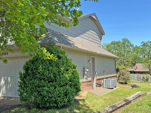 7333 W 36th St, Tulsa, OK 74107 - view of home's exterior featuring a garage, central AC, brick siding, and roof with shingles